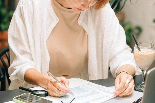 Small-business owner reviewing advertising costs, financial reports and campaign budgets with a calculator